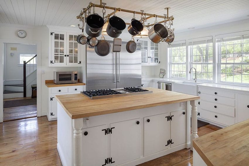 Country kitchen with white glass panel cabinets, maple wood countertops and island with built in range